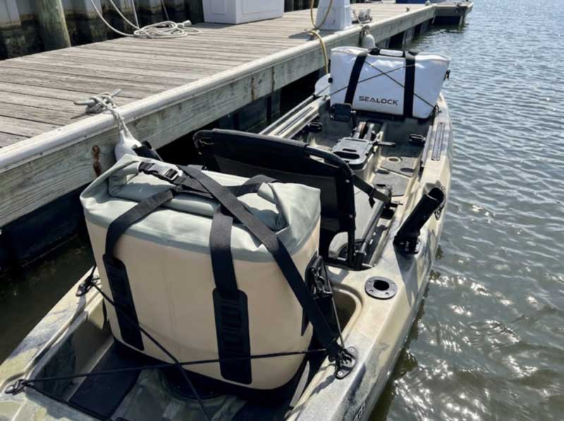 soft cooler strapped into a kayak tank well with a fish bag on the bow